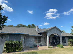 Gray shingle roof on a brick and stone home with an arched entry