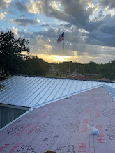 Silver metal roof going on at sunset with an American flag flying behind